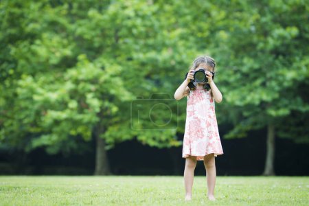 Little girl holding a single lens reflex camera