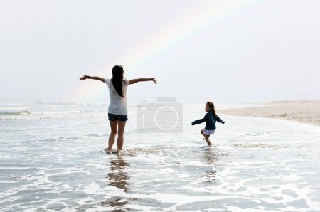 Mutter und Tochter spielen am Strand des Regenbogens