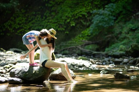 Téléchargez les photos : Mère et fille jouant dans le ruisseau de montagne - en image libre de droit