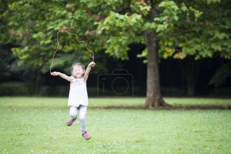 Foto de Chica jugando con saltar la cuerda en el parque - Imagen libre de derechos