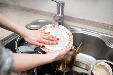 Téléchargez les photos : Les mains de la femme lavant beaucoup de vaisselle - en image libre de droit
