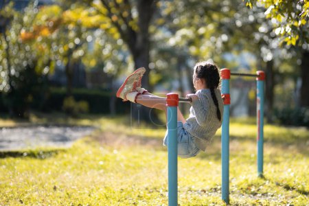 Foto de Chica jugando barra horizontal en el parque de otoño - Imagen libre de derechos
