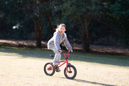 Téléchargez les photos : Mignonne petite fille asiatique chevauchant un vélo - en image libre de droit