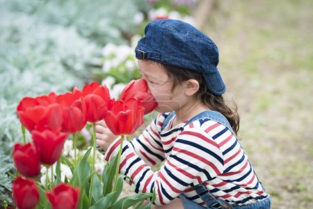 Foto de Hermosa asiática niña con rojo tulipanes en jardín - Imagen libre de derechos