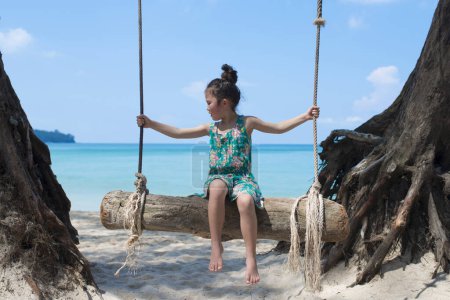 Téléchargez les photos : Petite fille sur une balançoire dans la plage - en image libre de droit