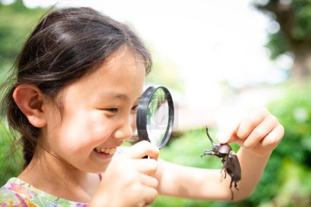 Téléchargez les photos : Asiatique fille regarder bug avec loupe - en image libre de droit
