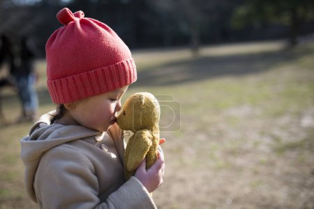 Téléchargez les photos : Petite fille avec un ourson dans le parc - en image libre de droit