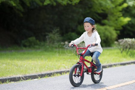Téléchargez les photos : Asiatique petite chinoise fille équitation vélo - en image libre de droit