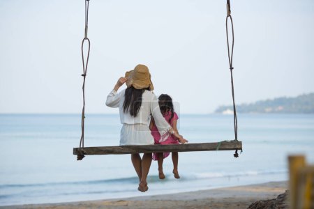 Foto de Madre e hija jugando en el columpio de playa - Imagen libre de derechos