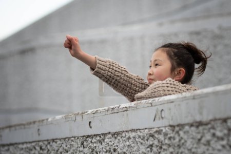 Téléchargez les photos : Une fille lève la main en regardant loin - en image libre de droit
