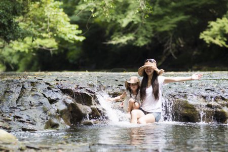 Téléchargez les photos : Mère et fille jouant sur le ruisseau de montagne - en image libre de droit