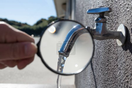 Téléchargez les photos : Agrandir l'eau sortant du robinet avec une loupe - en image libre de droit