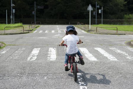 Téléchargez les photos : Mignonne petite fille asiatique équitation vélo dans la ville - en image libre de droit