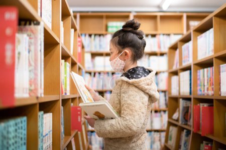 Photo for Girl choosing books in the library - Royalty Free Image
