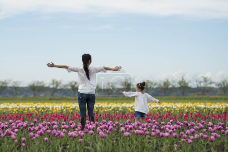 Foto de Feliz niña jugando en un campo de tulipanes - Imagen libre de derechos