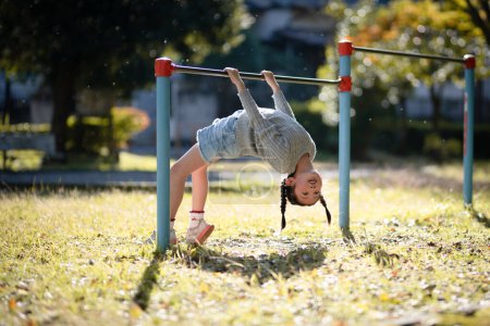 Foto de Chica jugando barra horizontal en el parque de otoño - Imagen libre de derechos