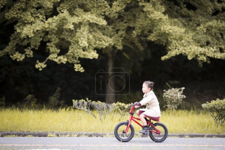 Little girl riding a red bicycle