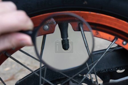 Téléchargez les photos : Agrandir la valve d'air d'un pneu de moto avec une loupe - en image libre de droit