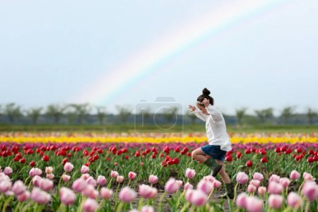 Téléchargez les photos : Fille jouer dans un champ de fleurs arc-en-ciel - en image libre de droit