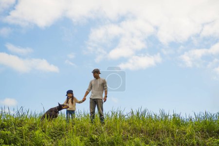Photo for Father, daughter and dog playing in the meadow - Royalty Free Image