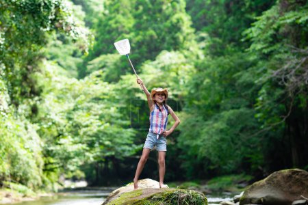 Téléchargez les photos : Un enfant avec un filet à insectes dans un ruisseau de montagne - en image libre de droit