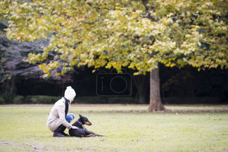 Photo for Doberman and woman relax on the lawn - Royalty Free Image