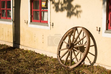 Foto de Una vieja rueda de carro de madera apoyada en una pared de piedra - Imagen libre de derechos