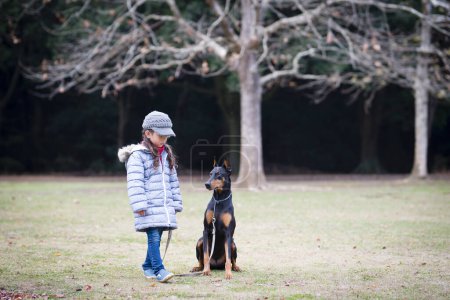 Photo for Little girl playing with Doberman - Royalty Free Image