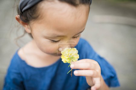 Téléchargez les photos : Petite fille pour sentir le parfum de la fleur - en image libre de droit