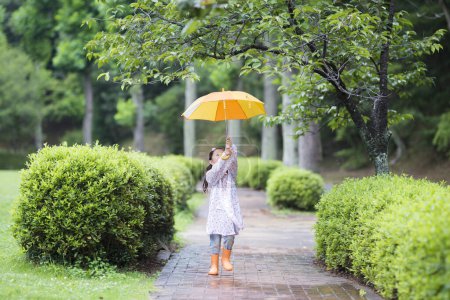 Glückliches kleines Mädchen, das mit einem Regenschirm läuft