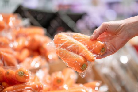 Mano de mujer eligiendo zanahorias en el supermercado