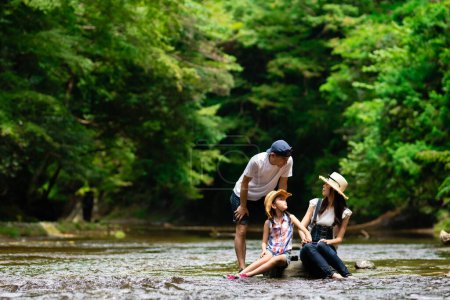 Téléchargez les photos : Père, mère et fille jouant dans le ruisseau de montagne - en image libre de droit