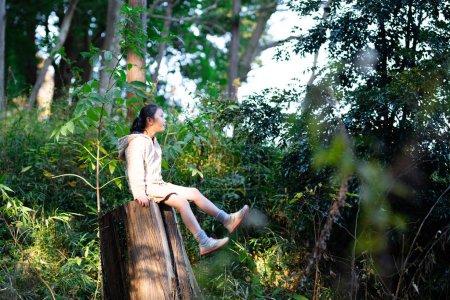 Foto de Lindo asiático niña en el árbol tronco en el jardín - Imagen libre de derechos
