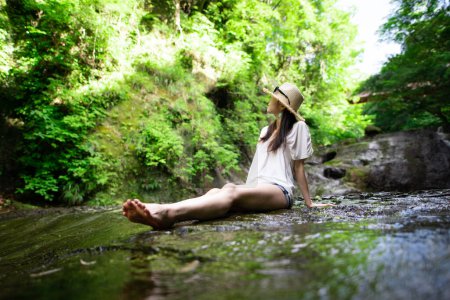 Téléchargez les photos : Une femme se relaxant dans un ruisseau de montagne - en image libre de droit