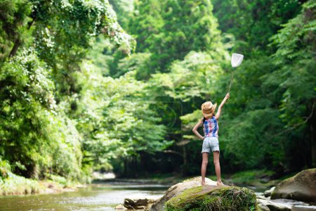 Un enfant avec un filet à insectes dans un ruisseau de montagne
