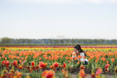 Téléchargez les photos : Femme relaxante dans le champ de tulipes - en image libre de droit