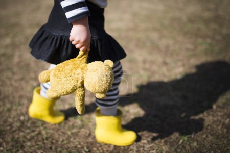 Téléchargez les photos : Petite fille marche avec ours en peluche dans le parc - en image libre de droit