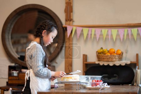 Téléchargez les photos : Petite fille faire une tarte dans la cuisine. - en image libre de droit