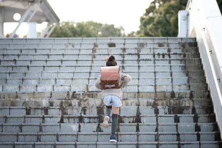Foto de Lindo asiático niña con mochila corriendo en escaleras - Imagen libre de derechos