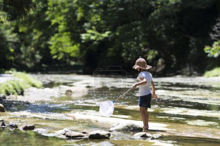 Téléchargez les photos : Mignonne petite fille asiatique pêche sur le lac - en image libre de droit