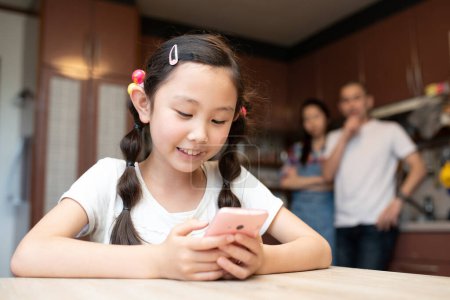 Téléchargez les photos : Les parents inquiets à propos d'une fille regardant un smartphone - en image libre de droit