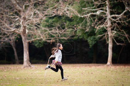 Téléchargez les photos : Mignonne asiatique petite fille avec saut de corde dans la forêt - en image libre de droit