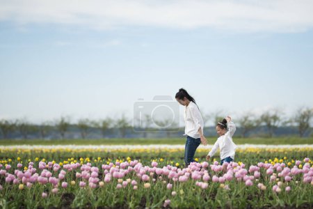 Téléchargez les photos : Bonne petite fille jouant dans un champ de tulipes - en image libre de droit