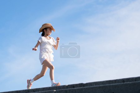 Téléchargez les photos : Mignonne petite fille asiatique courir dans le parc le jour ensoleillé - en image libre de droit
