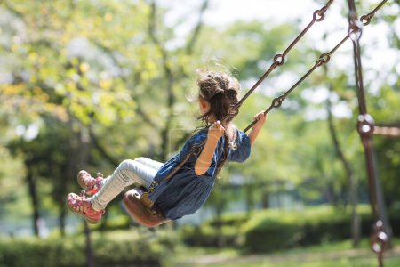 Photo for Girl playing on a swing in park - Royalty Free Image