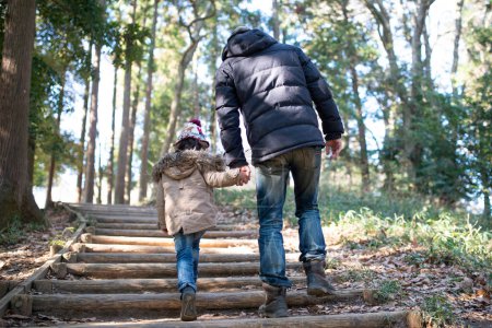 Téléchargez les photos : Père et fille marchent dans les bois en se tenant la main - en image libre de droit