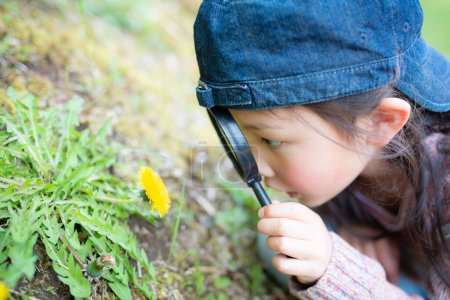 Téléchargez les photos : Portrait d'enfant mignon regardant sur la fleur avec loupe - en image libre de droit