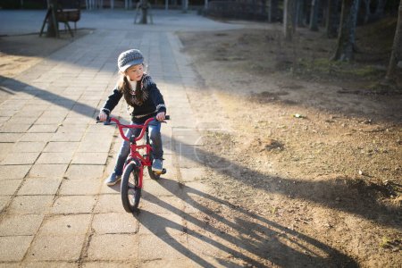 Téléchargez les photos : Mignon asiatique petite fille vélo équitation - en image libre de droit