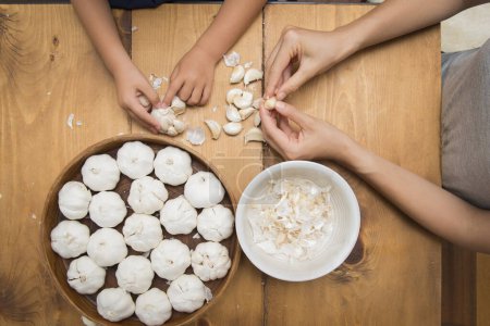 Téléchargez les photos : Mains de parents et d'enfants pour cuisiner l'ail - en image libre de droit