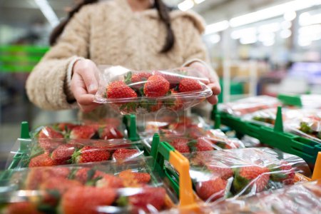 Téléchargez les photos : Fille ramasser des fraises dans un supermarché - en image libre de droit